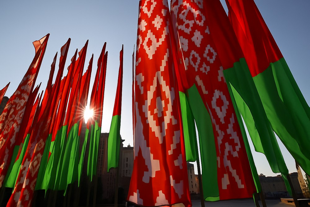 Флаги Беларуси советского образца на государственном мероприятии, солнце пробивается сквозь ткань